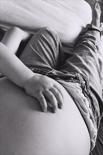 Chloe's sweet toddler's hand on her pregnant belly