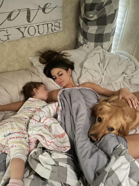 Stacey laying in bed with her toddler and dog